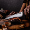 German steel cold forged Chefs knife cutting through pork ribs.