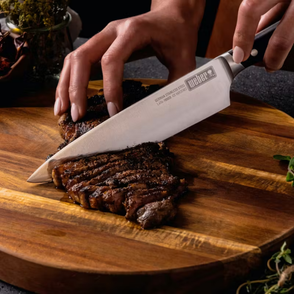 German steel cold forged Chefs knife cutting through steak.